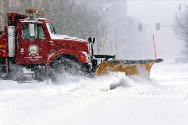 A city snow plow clears a street of snow in an almost deserted downtown as strong winds and snow move through the Midwest on Sunday.
