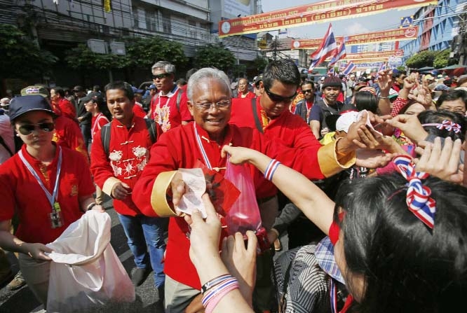 Anti-government protest leader Suthep Thaugsuban, center, is offered donations from supporters during a march through the China Town area of Bangkok, Thailand on Saturday.