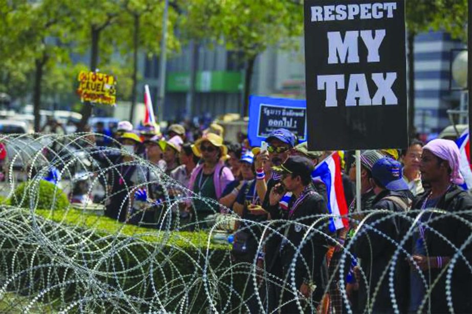 Anti-government protesters gather near a barbed-wire fence at a government office where Prime Minster Yingluck Shinawatra had been holding a meeting in Bangkok.