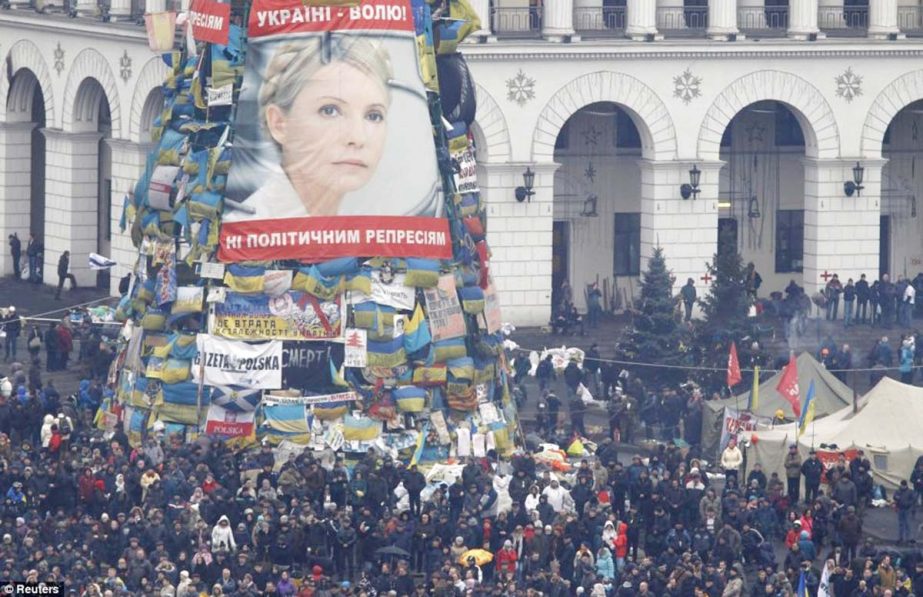 Anti-government protesters stand front of a poster showing jailed Ukrainian opposition leader Yulia Tymoshenko in the Independence Square in Kiev.