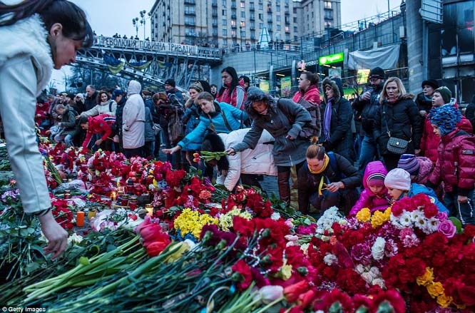 People place flowers at a makeshift memorial as they gather to commemorate the victims of the recent clashes in central Kiev.