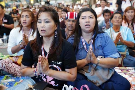 Anti-government protesters pray near the site of a bomb blast shortly after the explosion in Bangkok