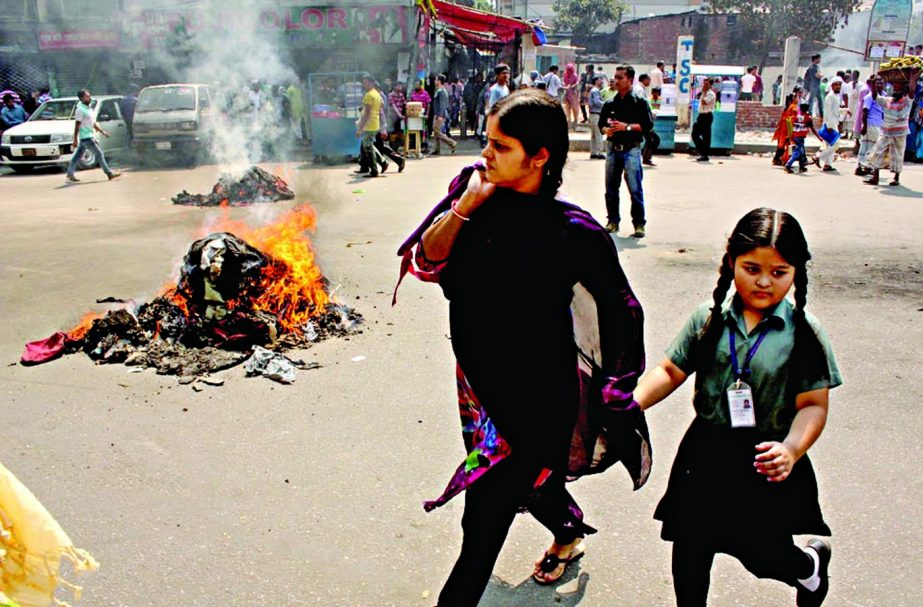 Worried mother along with her school going daughter trying to hastily cross the road where agitating JnU students set fire demanding recovery of the dormitories on Thursday.