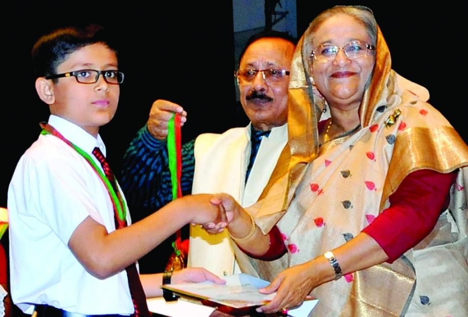 Prime Minister Sheikh Hasina handing over Primary Education Medal to a meritorious student at Osmani Memorial Auditorium in the city on Sunday. BSS photo