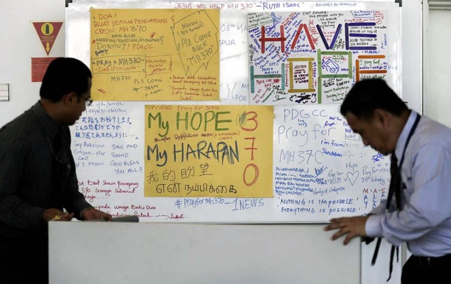 Airport staff move a white board plastered with messages of hope and encouragement to all involved with the missing Malaysia Airlines jet, MH370, at the Kuala Lumpur International Airport on Tuesday.