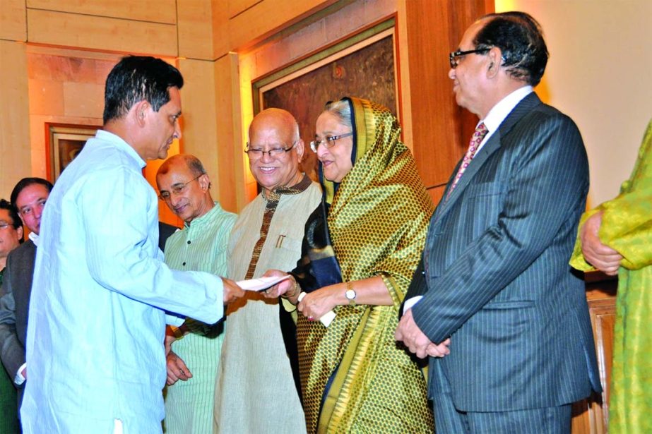 Chairman of Shahjalal Islami Bank Limited AK Azad handed over a Cheque of Tk 1 crore to Prime Minister Sheikh Hasina at Ganobhaban recently to sponsor "Lakho Konthe Sonar Bangla"" programme. Finance Minister Abul Maal Abdul Muhith and Advisor of Power &"