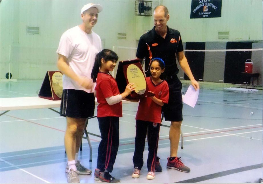 Mahvish Ishtique, a student of Grade III of Canadian International School (CIS) and Mahea Sehrin, a student of Grade III of CIS receiving the championship trophy of the AIDS Elementary School Girls' Badminton Tournament from John Fry of American Internat