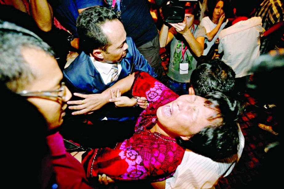 A Chinese relative of a passenger aboard a missing Malaysia Airlines plane is carried out by security officials as she protests before a press conference at a hotel in Sepang, Malaysia, Wednesday.