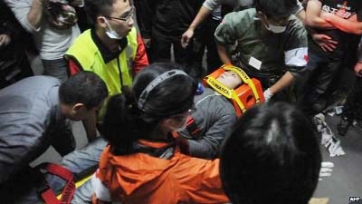 Paramedics carry an injured protester on a stretcher at the Executive Yuan in Taipei early on Monday