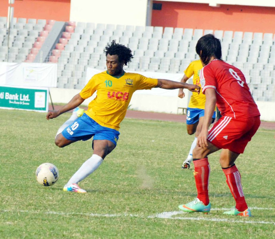 Sony Norde (left) of Sheikh Jamal Dhanmondi Club hitting a ball while an unidentified player (right) of Muktijoddha Sangsad Krira Chakra watching during the match of the Modhumoti Bank Independence Cup Football Tournament at the Bangabandhu National Stad