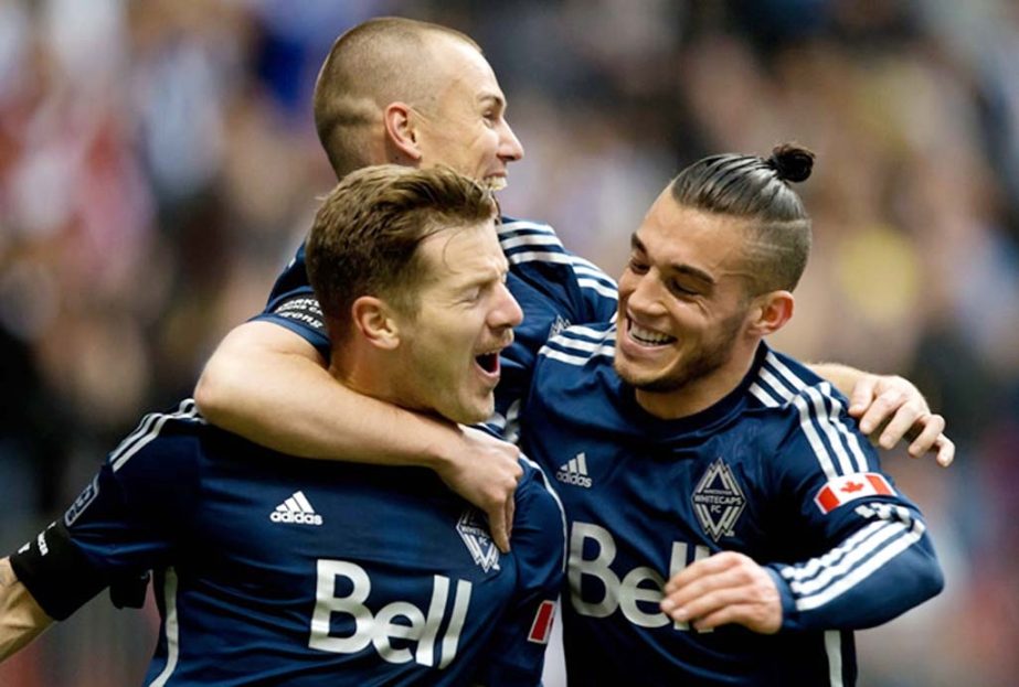 Vancouver Whitecaps' Jordan Harvey front left Kenny Miller top of Scotland and Russell Teibert celebrate Harvey's goal against the Houston Dynamo during the first half of an MLS soccer game in Vancouver, British Columbia on Saturday.