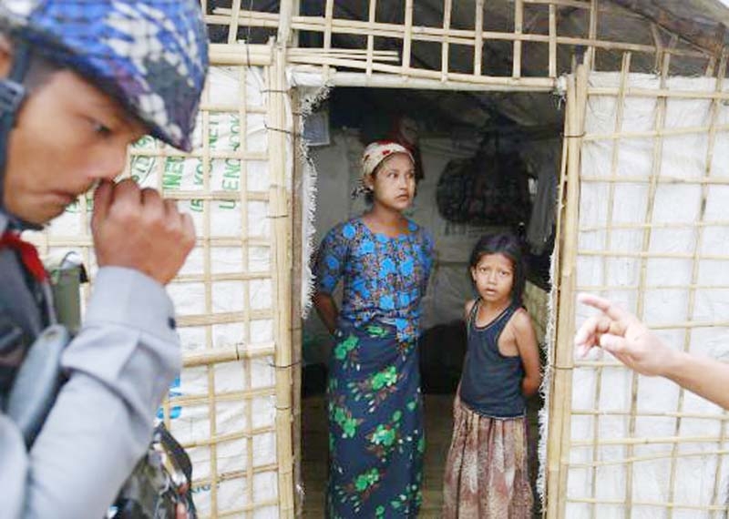 A family stand at the entrance of their temporary shelter as the government embarks on a national census at a Rohingya refugee camp in Sittwe, the capital of Rakhine State on Tuesday.