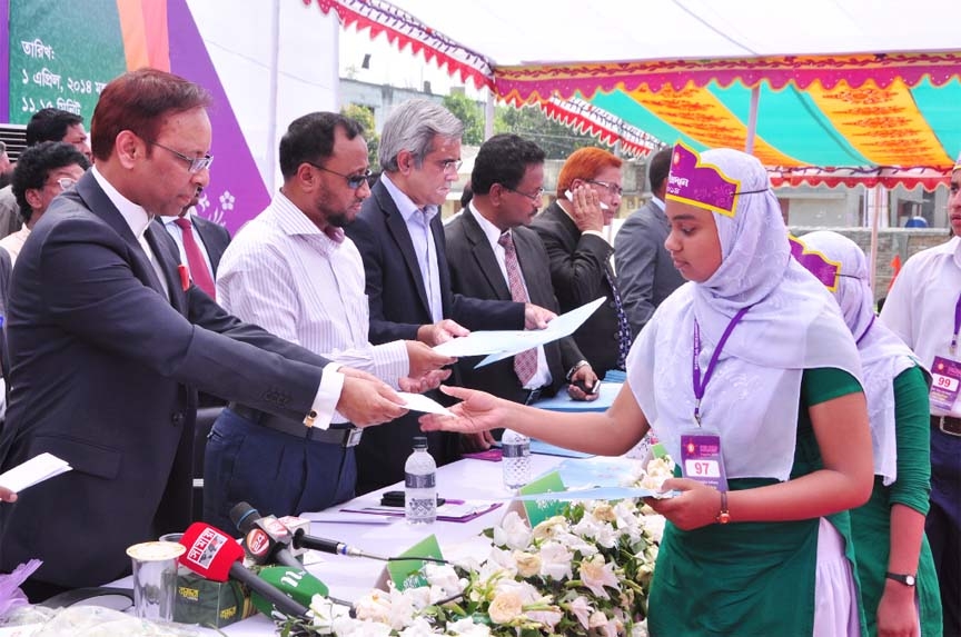 Students receiving scholarship papers and certificates given by Khwaja Mozammel Hoque (R) Foundation at Ullapara Merchants Pilot High School and Technical College premises in Sirajgonj on Tuesday.