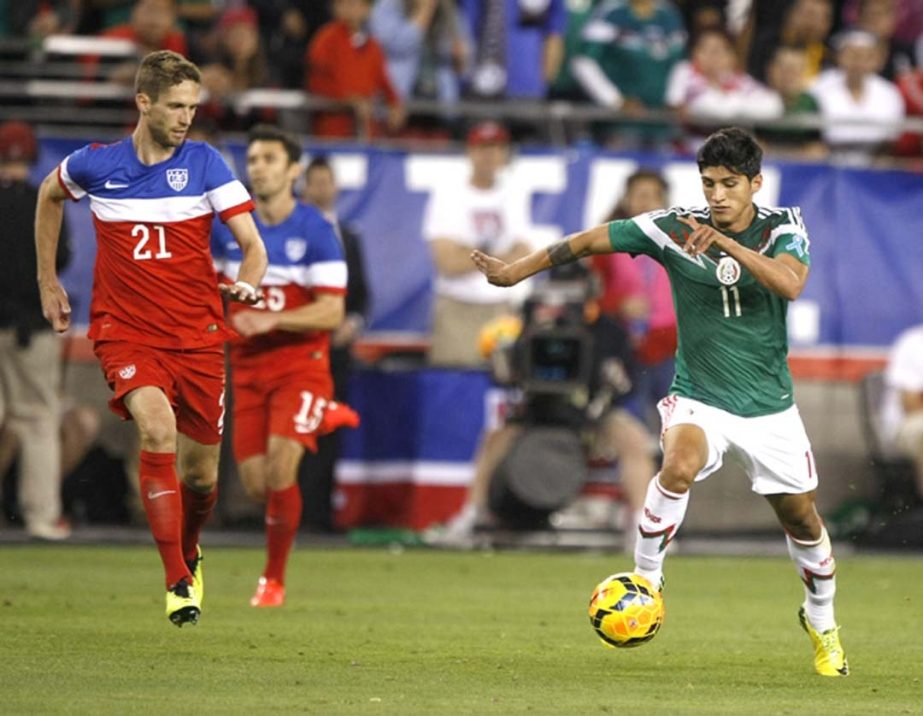 Mexico forward Alan Pulido (11) carries the ball in front of US defenseman Clarence Goodson (21) during the second half of an international friendly soccer match against the US in Glendale, Ariz on Wednesday. The game ended in a 2-2 draw.