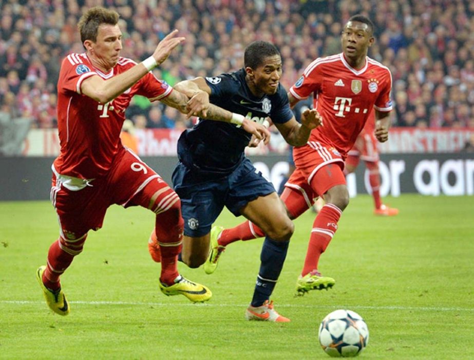 Manchester United's Antonio Valencia (center) and Bayern's Mario Mandzukic of Croatia (left) challenge for the ball during the Champions League quarterfinal second leg soccer match between Bayern Munich and Manchester United in the Allianz Arena in Muni