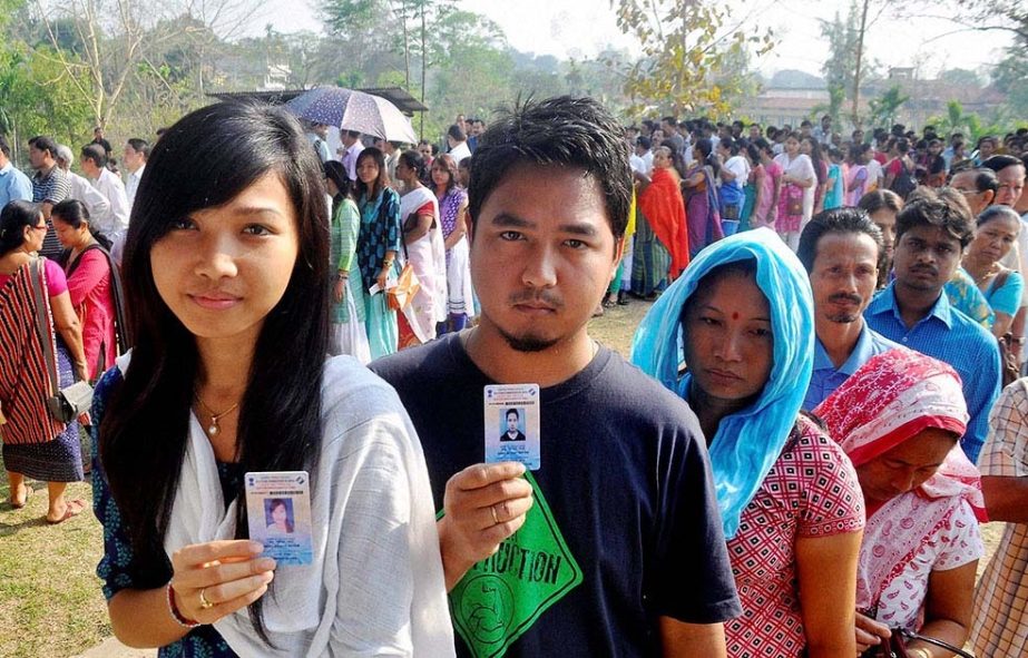 People show their voter identity cards as they wait in queues to cast their votes for Lok Sabha polls at a polling station, at Diphu in Karbi Anglong district of Assam.