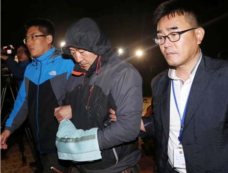 Oh Yong-suck, center, a crew member of the sunken ferry Sewol in the water off the southern coast, leaves a court which issued his arrest warrant in Mokpo, south of Seoul, South Korea on Saturday.