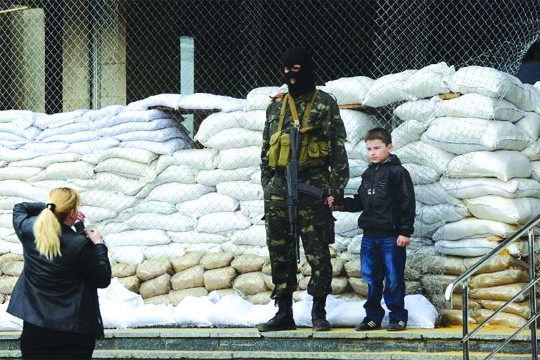 A woman takes a picture of her son standing by an armed man in military fatigues guarding a barricade outside he regional administration building in the eastern Ukrainian city of Slavyansk on Sunday.