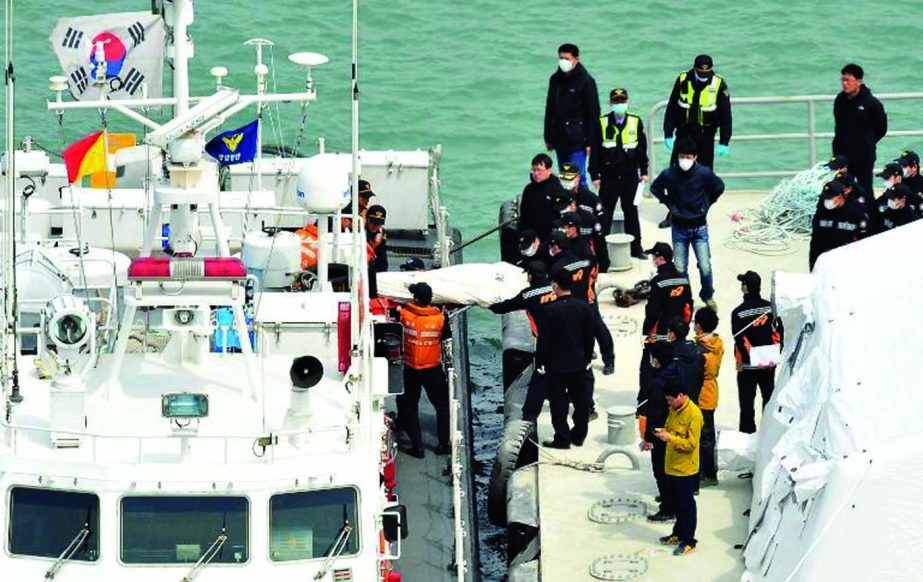 Rescuers carry the body of a victim recovered from the "Sewol"" ferry from a Korea Coast Guard ship (L) at a harbour in Jindo on Tuesday."