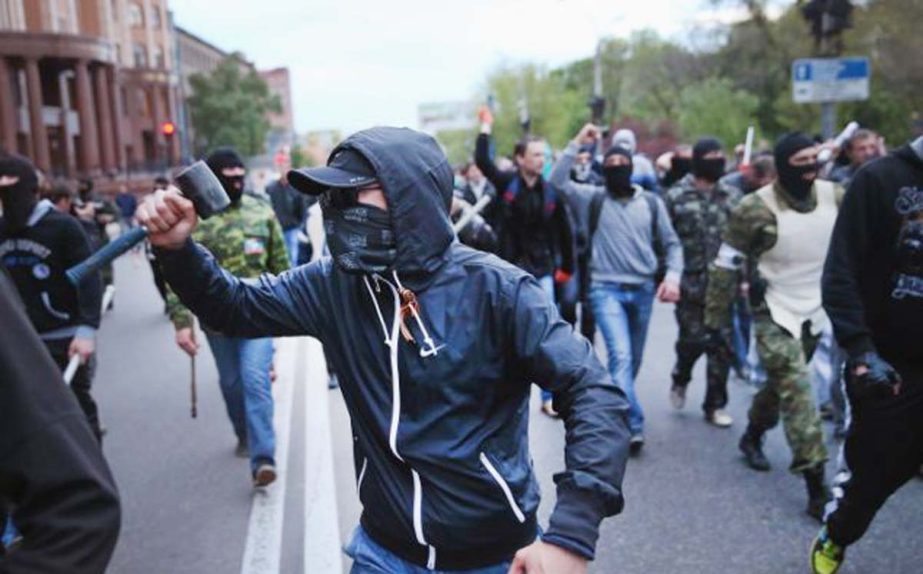 A masked Pro-Russian demonstrator holds a mallet while others in the background punch the air during the violence in the eastern city.