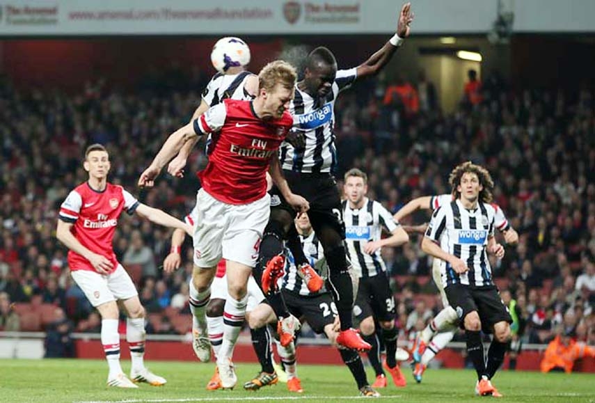 Arsenal's Per Mertesacker center (left) heads the ball under pressure from Newcastle's Cheick Tiote, center (right) during their English Premier League soccer match between Arsenal and Newcastle United at the Emirates stadium in London on Monday.