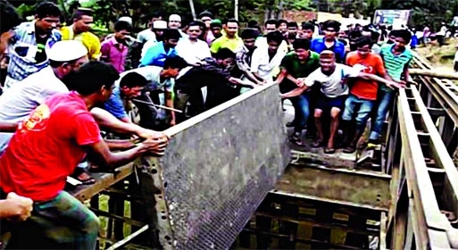 Agitating supporters of slain Fulgazi Upazila Chairman Ekramul Haque pulling out steel plates of Bailey Bridge on Feni-Parashuram road shortly after he was laid to rest on Wednesday.