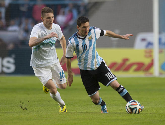 Argentina's Lionel Messi (right) fights for the ball with Slovenia's Rajko Rotman during their international friendly soccer match in La Plata, Argentina on Saturday. Argentina's team is leaving June 9 for Brazil to compete in the World Cup.