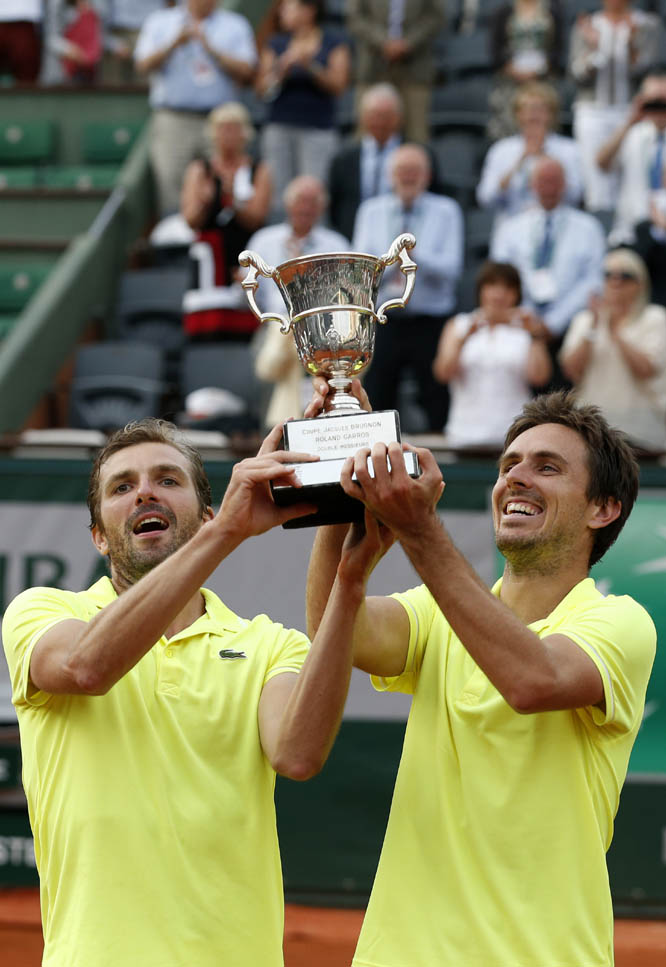 French pair Julien Benneteau (left) and Edouard Roger-Vasselin raise their trophy after defeating the Spanish pair Marcel Granollers and Marc Lopez during their men's doubles final match of the French Open tennis tournament at the Roland Garros stadium