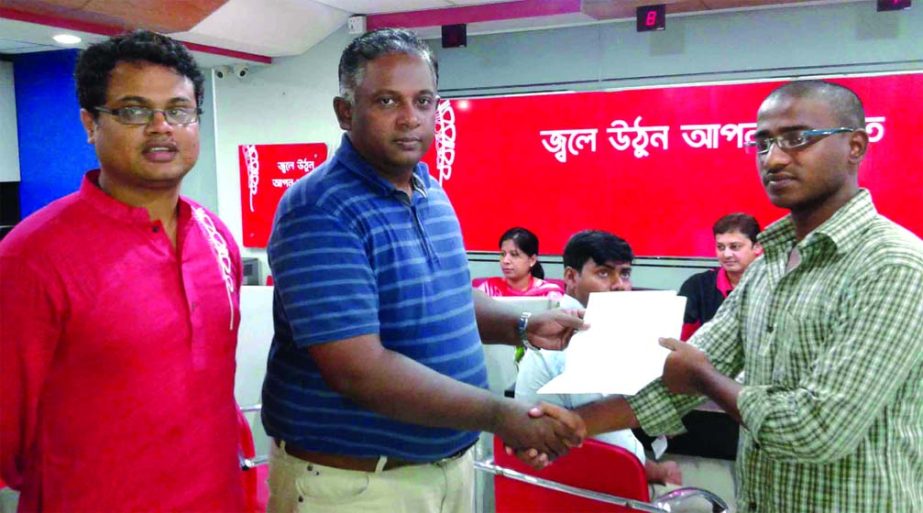 Mahtabuddin Ahmed, Chief Operating Officer of Robi Axiata Limited, handing over cheques of insurance claim to Md Sohel and Keshab Chandra at Robi's Walk-in-Centre at Agrabad in Chittagong recently.