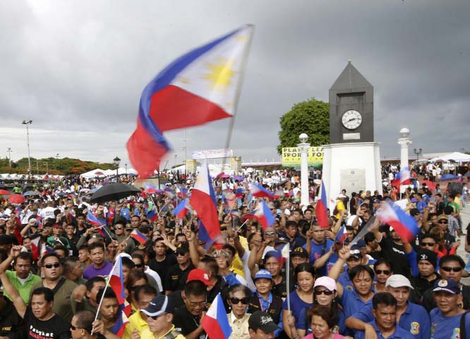 Filipinos wave Philippine flags following flag raising rites to celebrate the 116th anniversary of Philippine independence on Thursday.