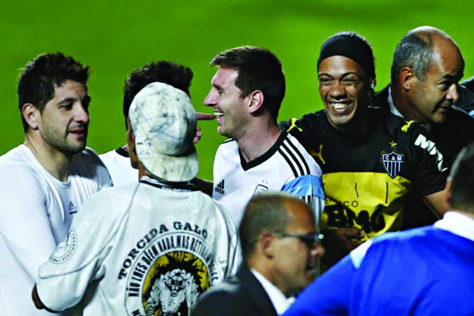 Argentina's Lionel Messi (center) and Argentina's goalkeeper Agustin Orion (left) interact with fans who invaded the pitch, one who resembles Brazilian soccer player Ronaldinho (second right) at the end of a training session at Independencia Stadium in