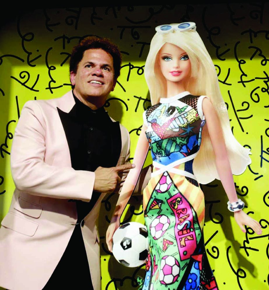In this photo taken on Thursday Brazilian neo-pop artist Romero Britto poses for photographers with a poster of his latest commission, a Barbie doll in honor of the World Cup in Miami Beach, Fla.