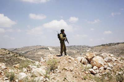 An Israeli soldier stands near the West Bank city of Hebron on Friday. Israeli soldiers searched the West Bank on Friday for three missing teenagers from nearby settlements, one of them a U.S. citizen, amid fears Palestinian militants abducted them, autho