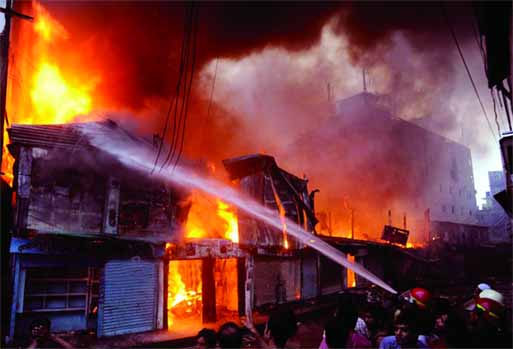 A devastating fire broke out at three wholesale clothing markets at Deobhagh area in N'ganj early Wednesday completely destroying goods worth crores of taka. Photo shows fire men trying to douse the flame.