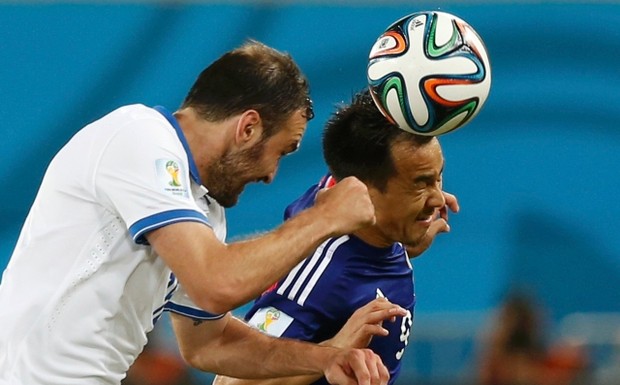Greece's Vasilis Torosidis (L) and Japan's Shinji Okazaki fight to head the ball during their 2014 World Cup Group C soccer match at the Dunas arena in Natal