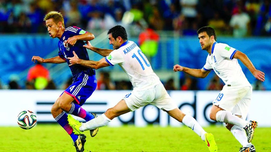 Keisuke Honda of Japan and Giorgos Karagounis of Greece compete for the ball during the 2014 FIFA World Cup Brazil Group C match between Japan and Greece at Estadio das Dunas in Natal, Brazil on Thursday.