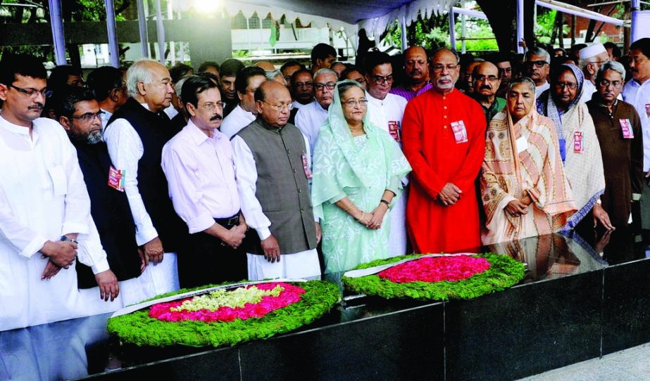 Prime Minister Sheikh Hasina along with party colleagues stand in solemn silence after placing floral wreaths at the portrait of Bangabandhu Sheikh Mujibur Rahman at Bangabandhu Bhaban in the city's 32 No Dhanmondi on Monday marking 65th founding anniver