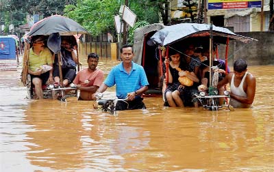 Rickshaw pullers wade through a waterlogged street after heavy rains in Guwahati.