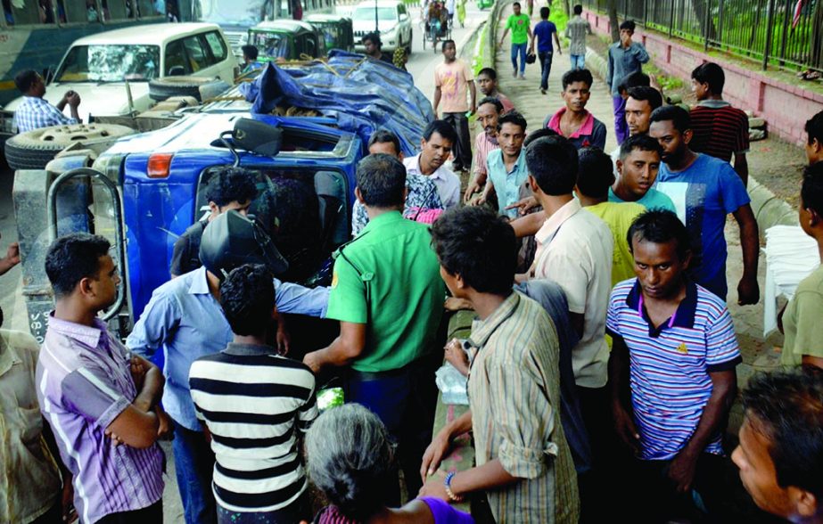 A pick-up van was turned over due to reckless driving in front of Ramna Park in the city on Saturday. People of the area look on.