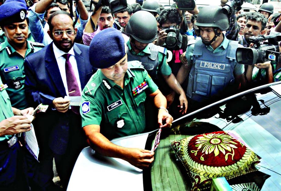 DMP Commissioner Benazir Ahmed pasting an anti-formalin leaflet and sticker on a private car in city's Motijheel area on Monday.