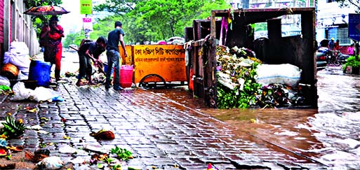 Garbage floating in Saturday's rain water at city's Rajarbagh Road near Malibagh crossing. A garbage dumping van of Dhaka South City Corporation (DSCC) is seen lying unattended spreading stinky smell.