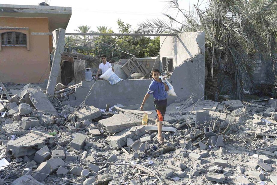 A Palestinian boy carries belongings from a house which police said was destroyed in an Israeli air strike in Khan Younis in the southern Gaza Strip on Tuesday.