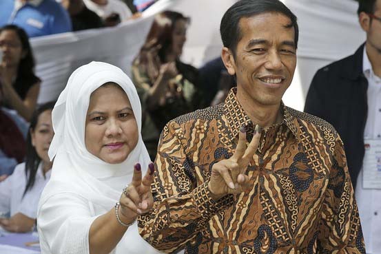 Indonesian presidential candidate Joko Widodo, popularly known as "Jokowi", left, and his wife Iriana, show their inked fingers after casting their votes during the presidential election in Jakarta on Wednesday.