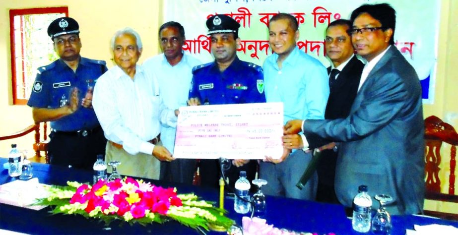 Moniruddin Ahmed, Director of the Board of Directors of Pubali Bank Ltd handing over a cheque of Tk5 lac last installment of Tk30,00,000 donation for Sylhet Zila Police auditorium and accompanying infrastructural development to Noore Alam Mina, Superinten