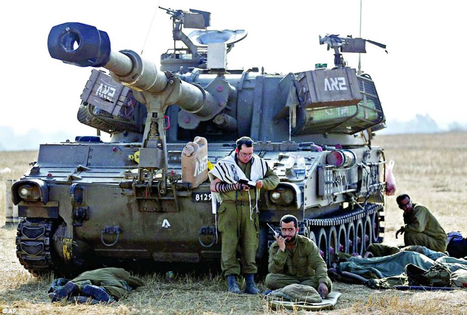 Possible ground attack: Israeli soldiers begin their day by sitting next to a mobile artillery unit close to the Israel-Gaza border on Friday morning.