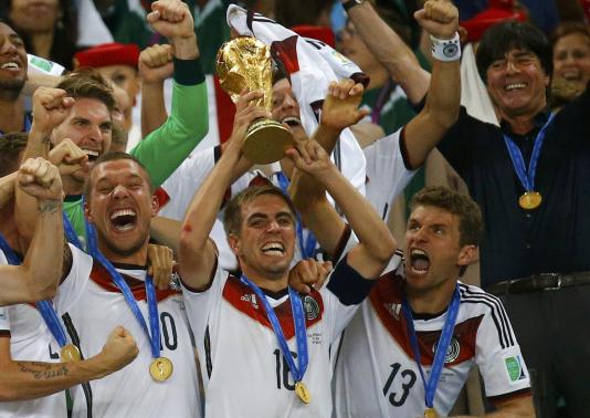 (L-R) Germany's Lukas Podolski, Philipp Lahm, Thomas Mueller and coach Joachim Loew celebrate with the World Cup trophy after the 2014 World Cup final between Germany and Argentina at the Maracana