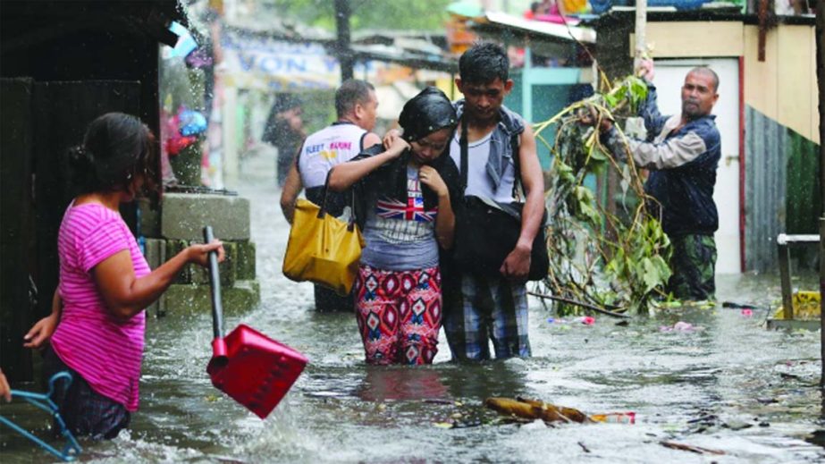 Residents wade through floods as they go back to their home in suburban Quezon city, north of Manila. Typhoon Rammasun killed 38 people, forced 530,000 to flee their homes and destroyed 7,000 homes.
