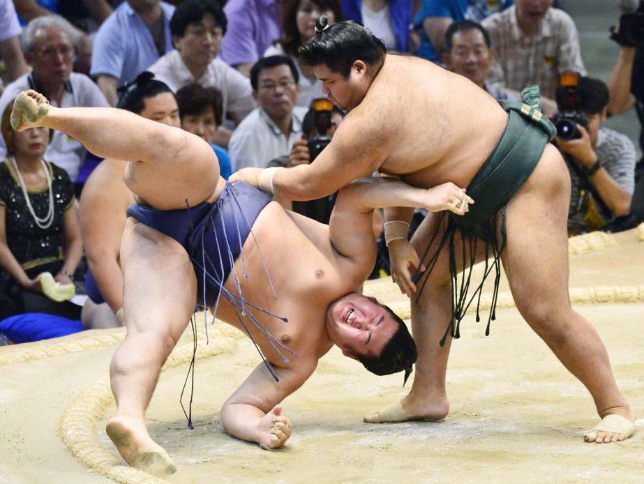 Sumo wrestler Takayasu (right) throws his opponent Tochinowaka on the ring to win their bout on the seventh day of the 15-day Nagoya Grand Sumo Tournament in Nagoya, central Japan on Saturday.