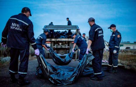 Rescue workers, pictured above, loaded the corpses onto trucks at the crash site in eastern Ukraine, which were then taken to refrigerated train carriages nine miles away.