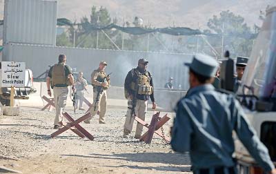 Afghan and foreign security forces inspect the site of a suicide attack at the deputy counter narcotic compound in Kabul.